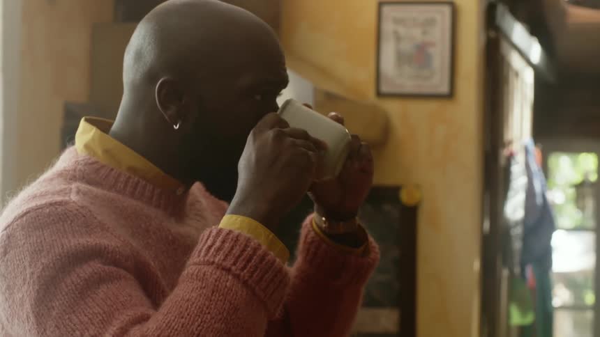 A man pours himself a cup of coffee only to spit it out after taking one sip