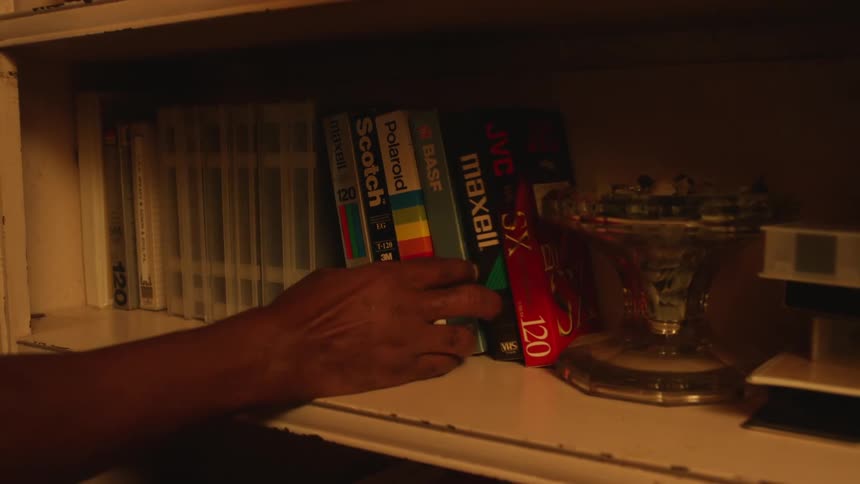A person takes a vhs tape off of a shelf