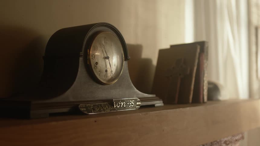 Vintage analog clock resting on a shelf in the wall inside a dimly lit room at home