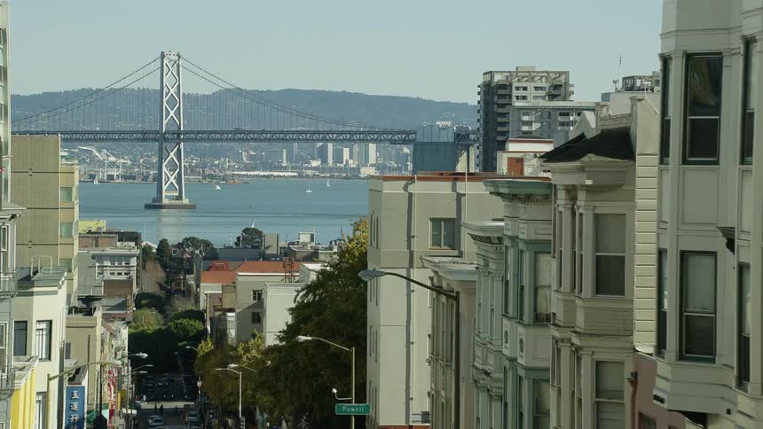 The bay bridge stands tall over the water nearby to the city san francisco