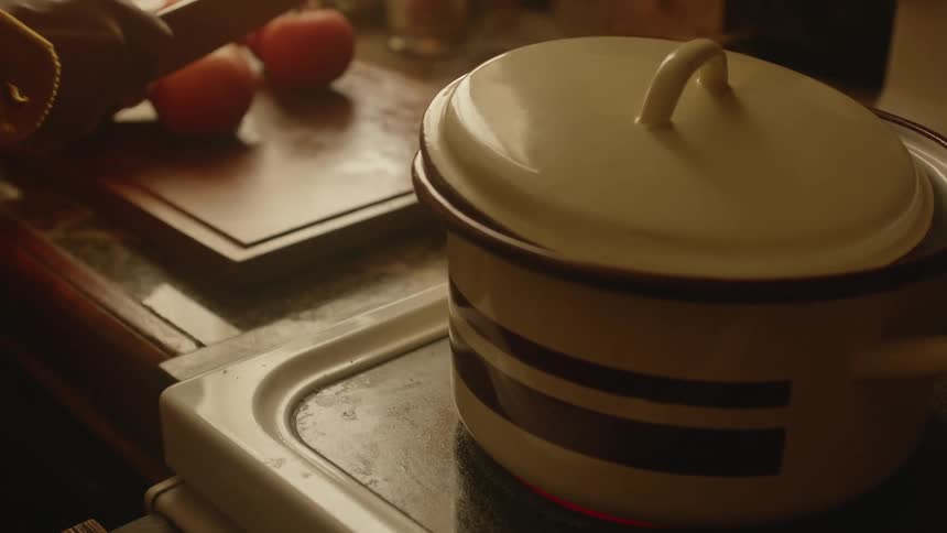 A person is preparing to cut some tomatoes next to a stove