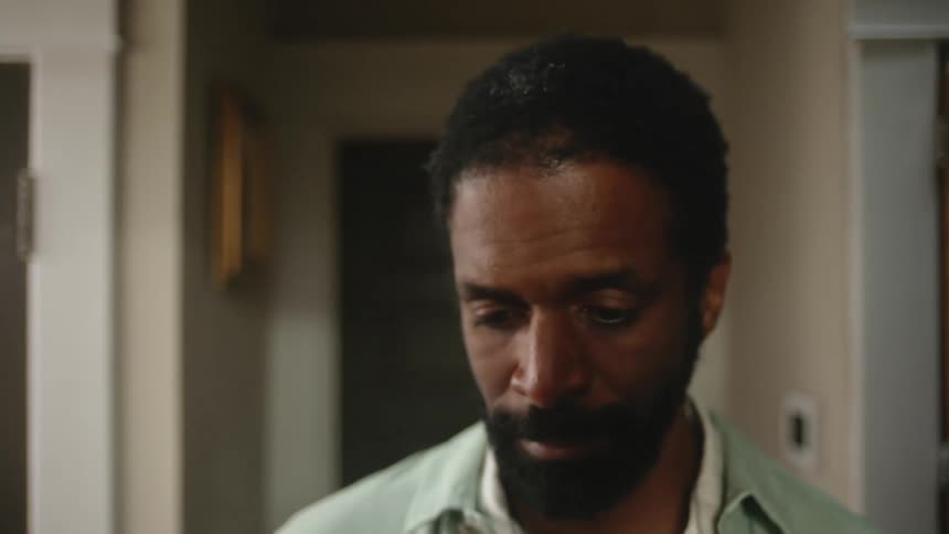 A man walks down the hallway of his house and stops