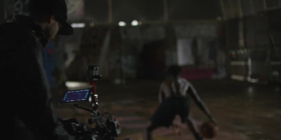 A man is being filmed dribbling a basketball at night