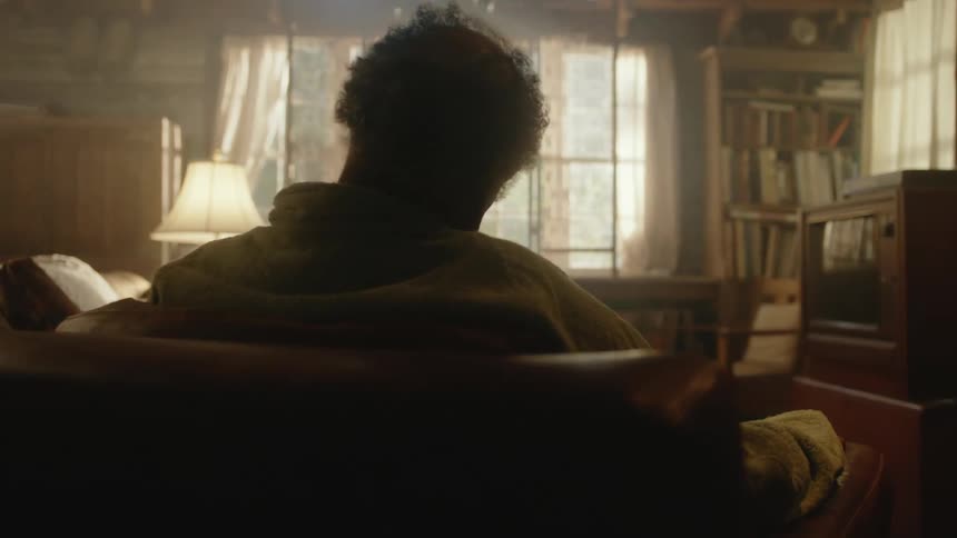 Elderly man sleeping on the couch in the dimly lit living room at home
