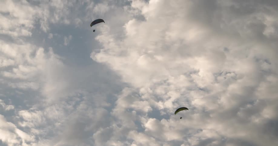Skydivers glide through the sky with parachutes drawn