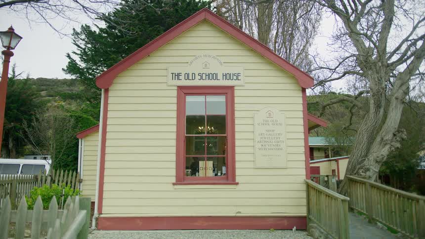 A school with signs on the front with trees the sky and clouds in the background