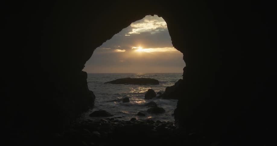 A view of water from the ocean crashing at a cave