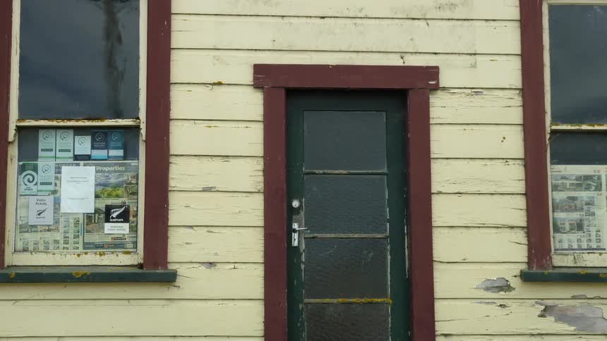 A building with a door and windows with the sky and clouds in the background