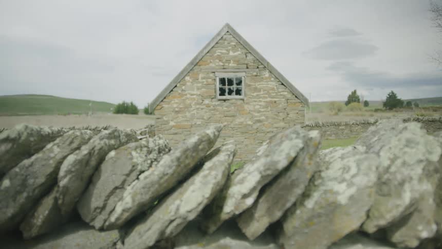 A stone wall is by the small house