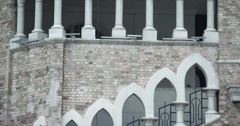 Brick building is decorated with white columns and arches and black iron work