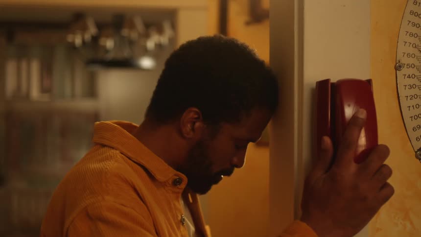 Man sits in the kitchen with an elderly man then gets up to answer the phone in another room