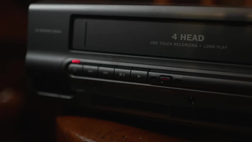 Someone inserts a video tape into a video recorder player