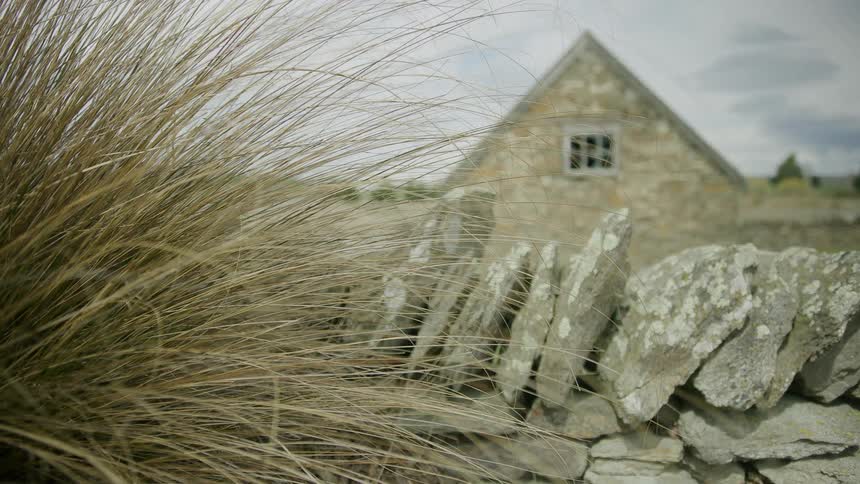 Stone country house with wall on a cloudy day