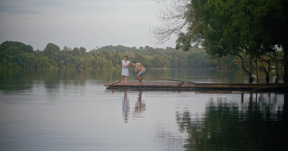 Two females stand on the end of a pier at a lake