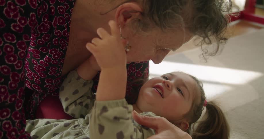 A grandmother holds her granddaughter on the ground