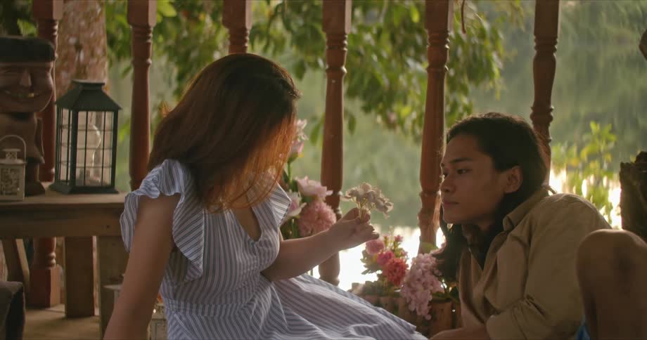 A boyfriend and girlfriend looking at flowers outdoors
