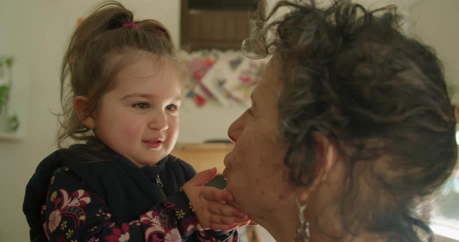 Granddaughter touches the wrinkles on her grandmother face at home