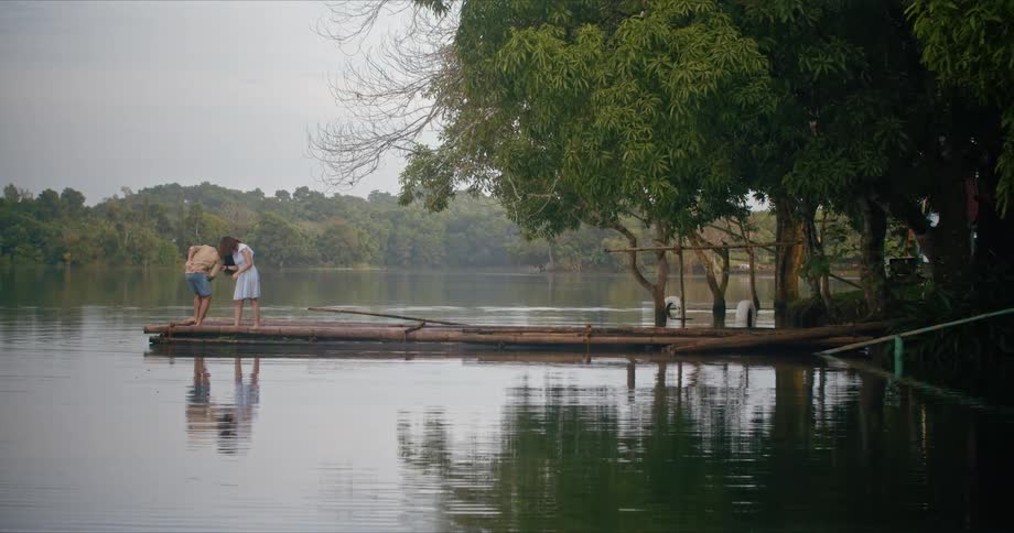 A man and woman dance and have fun together at the end of a lake pier
