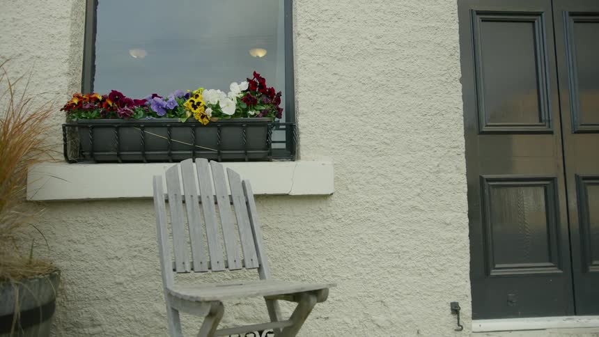 A chair with nobody in it outside of a house