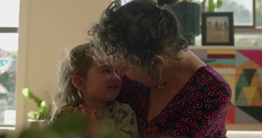 Grandmother tenderly talking to her granddaughter sitting at home