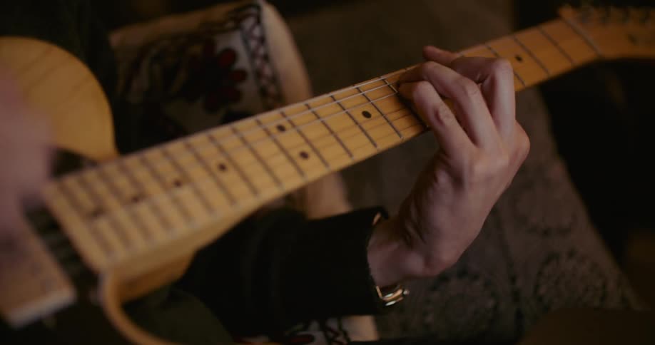A man is sitting and playing a guitar