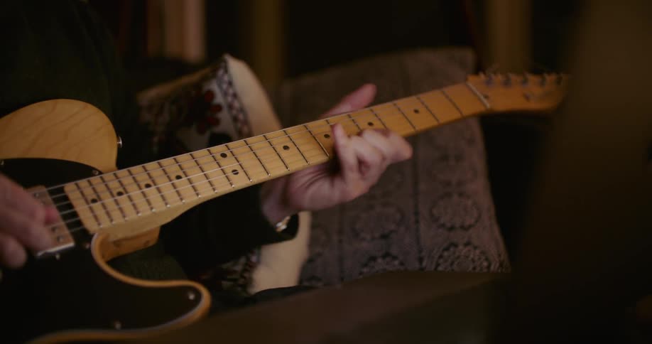 Guitarist sits near laptop playing guitar