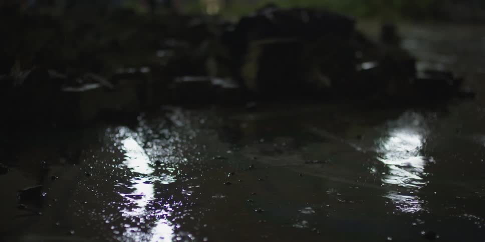 A foot walks over a sidewalk with raindrops dropping on it