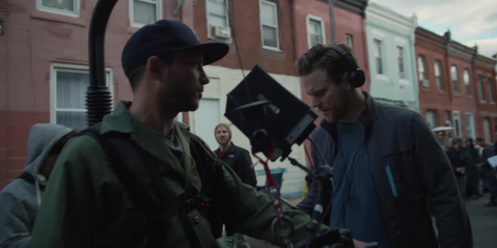 A film crew stands on a city sidewalk