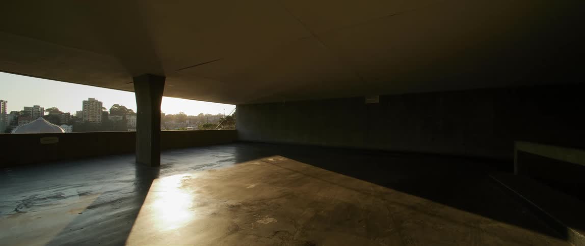 Sun shines across city through open side onto part of empty floor in parking structure