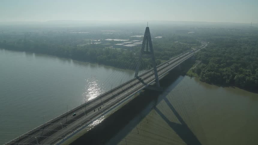 Traffic travels across a bridge spanning a large river during the day