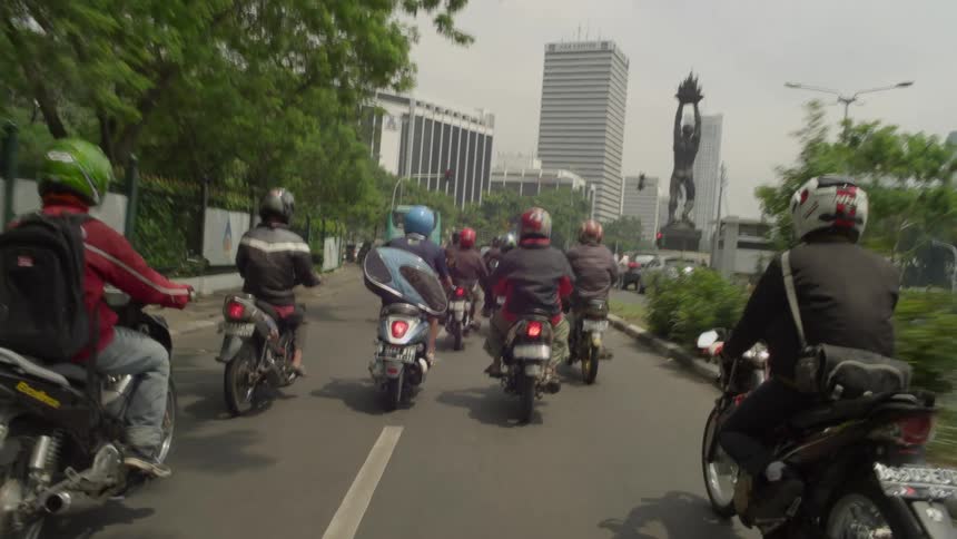 A group of bikers rides bikes on city highway
