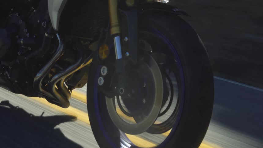 Person rides motorcycle along highway riding near the double yellow line