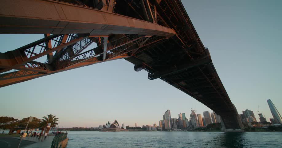 A bridge over a river with a city skyline the sky and clouds in the background