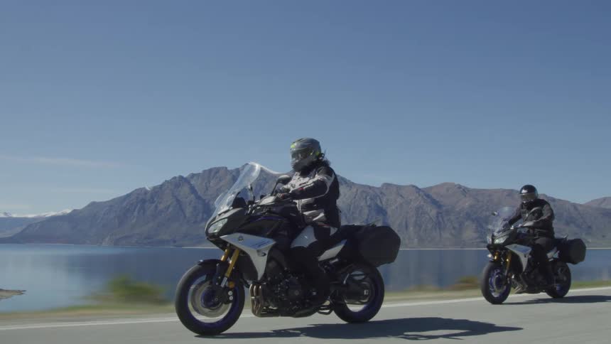 Two people ride on the road by the lake together