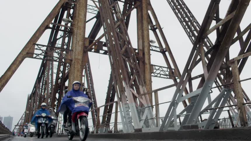 Group of people riding motorcycles on a rainy day over a bridge near the city