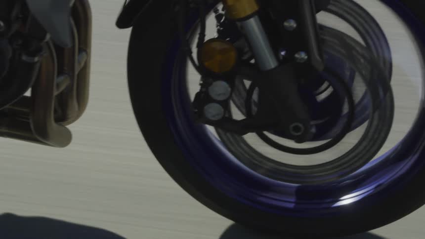 Motorcycle wheel spinning while riding over the road at daytime