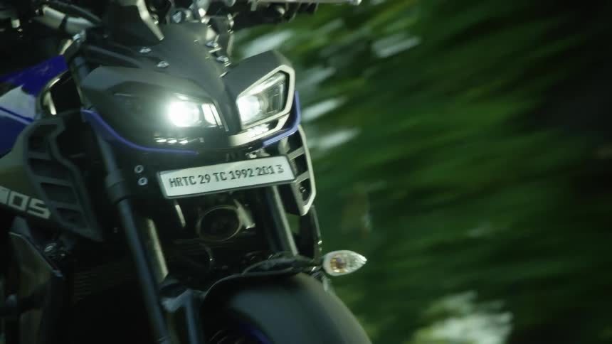 A person drives a motorcycle down a street