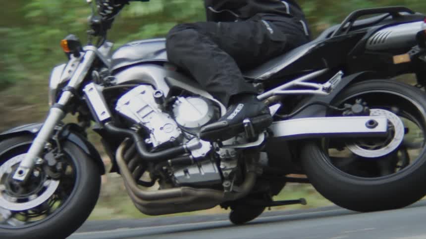 Man with red crash helmet black jacket and pants rides motorcycle and takes the bend on the highway