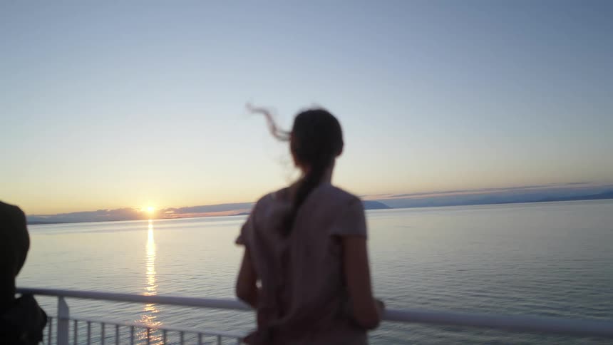 A woman and a man standing by a handrail with a lake the sky and clouds in the background