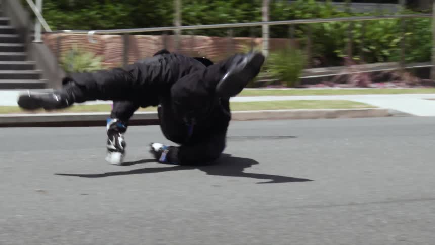Man with blue helmet black jacket and pants falls of motorcycle and rolls along the road