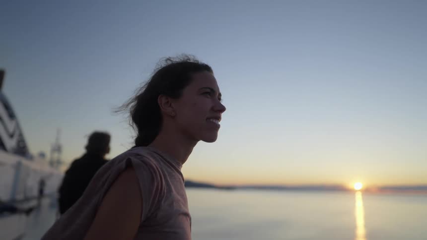 Wind blows through a womans hair as she stands on a pier