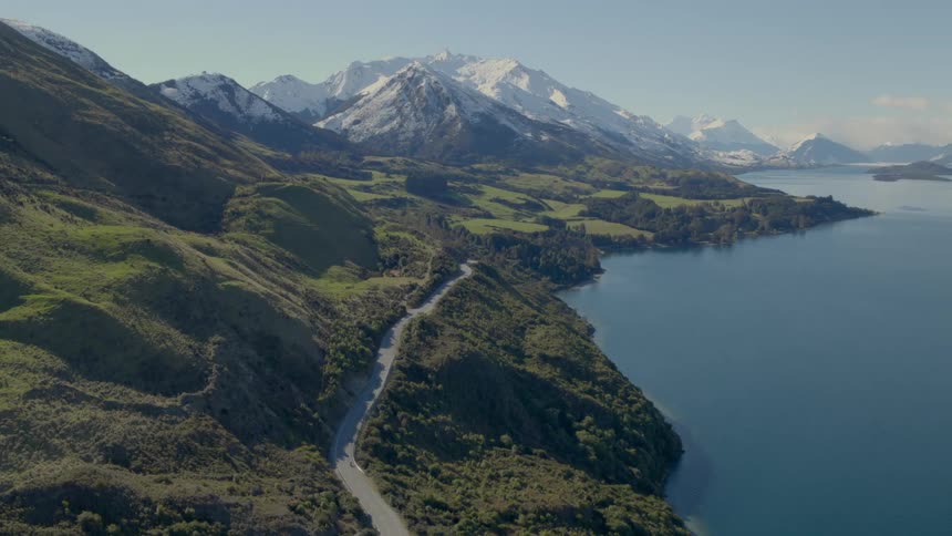 Cyclists ride down a curvy mountain road along the coast