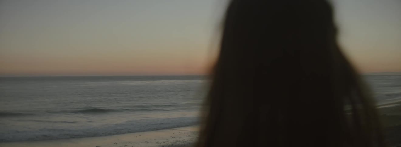 A woman looks at a sunset on the beach
