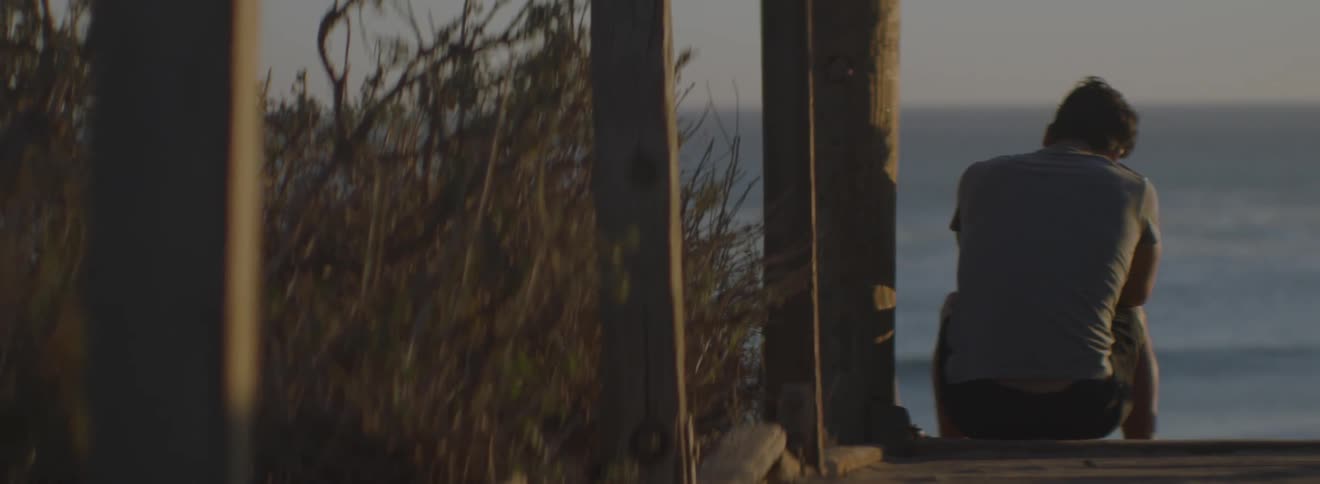 A man is sitting on a pier at sunset