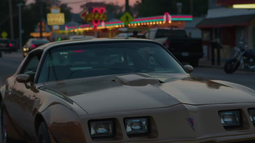 Neon lights on a classic car glow and flash while cars travel past