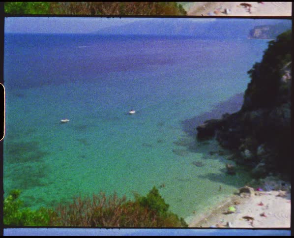 Small boats over the clear green water near the coast of a beach caught on vintage film