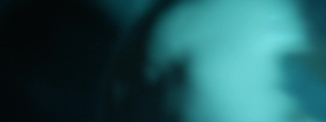 Sweaty bare chested man sways back and forth dancing under blue colored lights