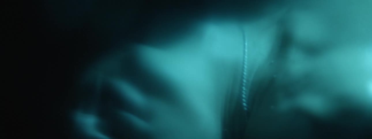 A man with a necklace in a dark room