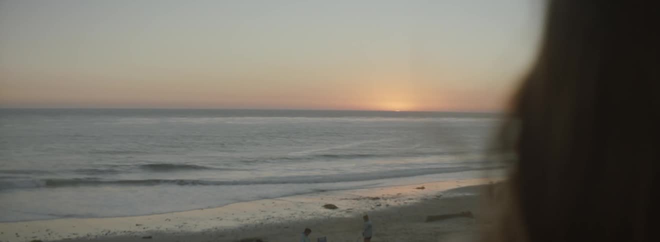 A woman looks toward a beach at sunrise