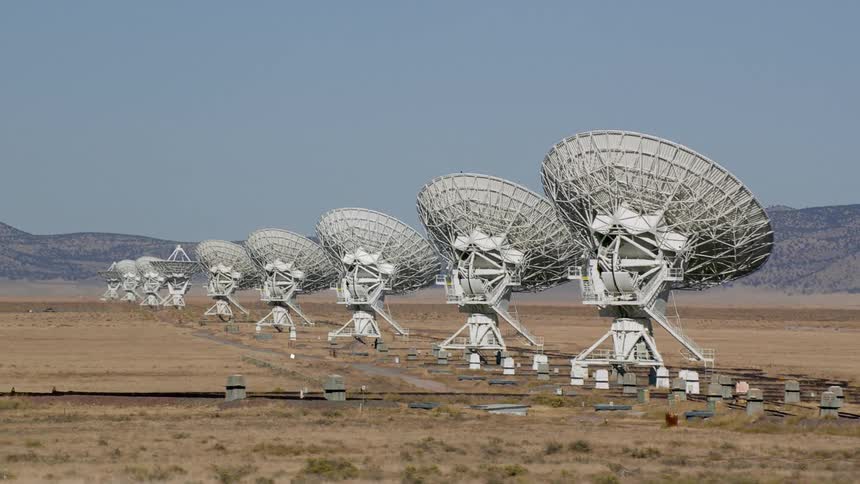 Several satellite dishes in a line in a remote area